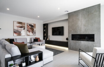 Contemporary living room with a stone feature wall with linear fireplace, sectional sofa, floating dark media console, and modern accent seating.