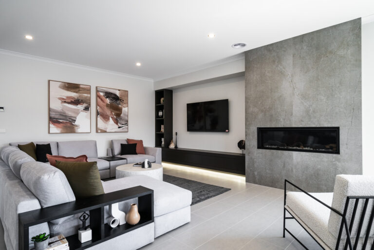 Contemporary living room with a stone feature wall with linear fireplace, sectional sofa, floating dark media console, and modern accent seating.