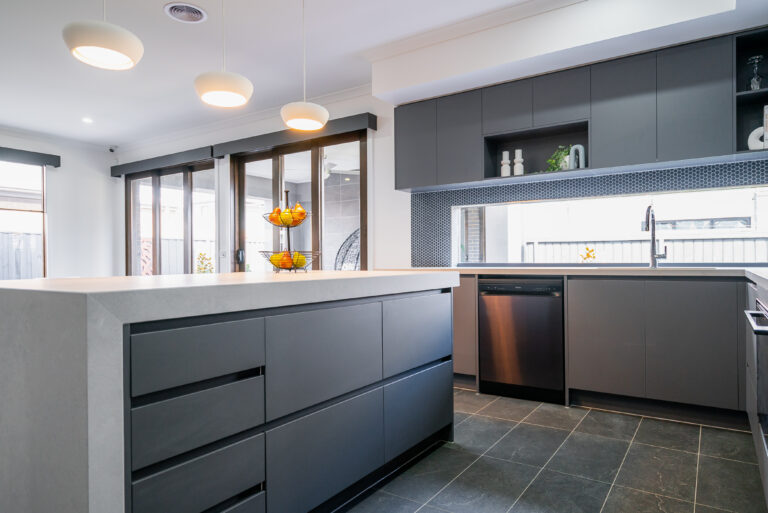 Modern kitchen featuring a waterfall island bench with charcoal cabinetry, dark grey tile floor, black mosaic backsplash, and pendant lighting.